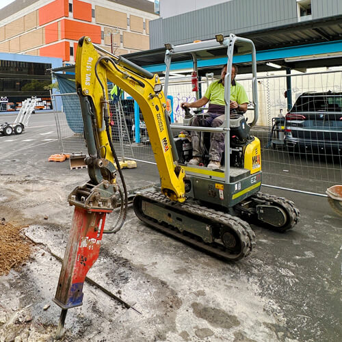 Maxi Equipment Hire - Wet hire page image of Wacker Neuson 1.8 Ton Excavator with a rock breaker in action on an Adelaide city street.